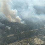 Aerial view of a forest fire with smoke rising over woodland